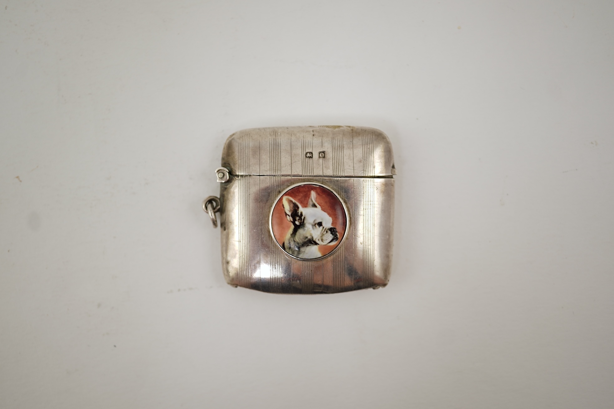 A George V silver and enamel vesta case, by Henry Hyde Aston, the inset circular enamel plaque decorated with a French bulldog